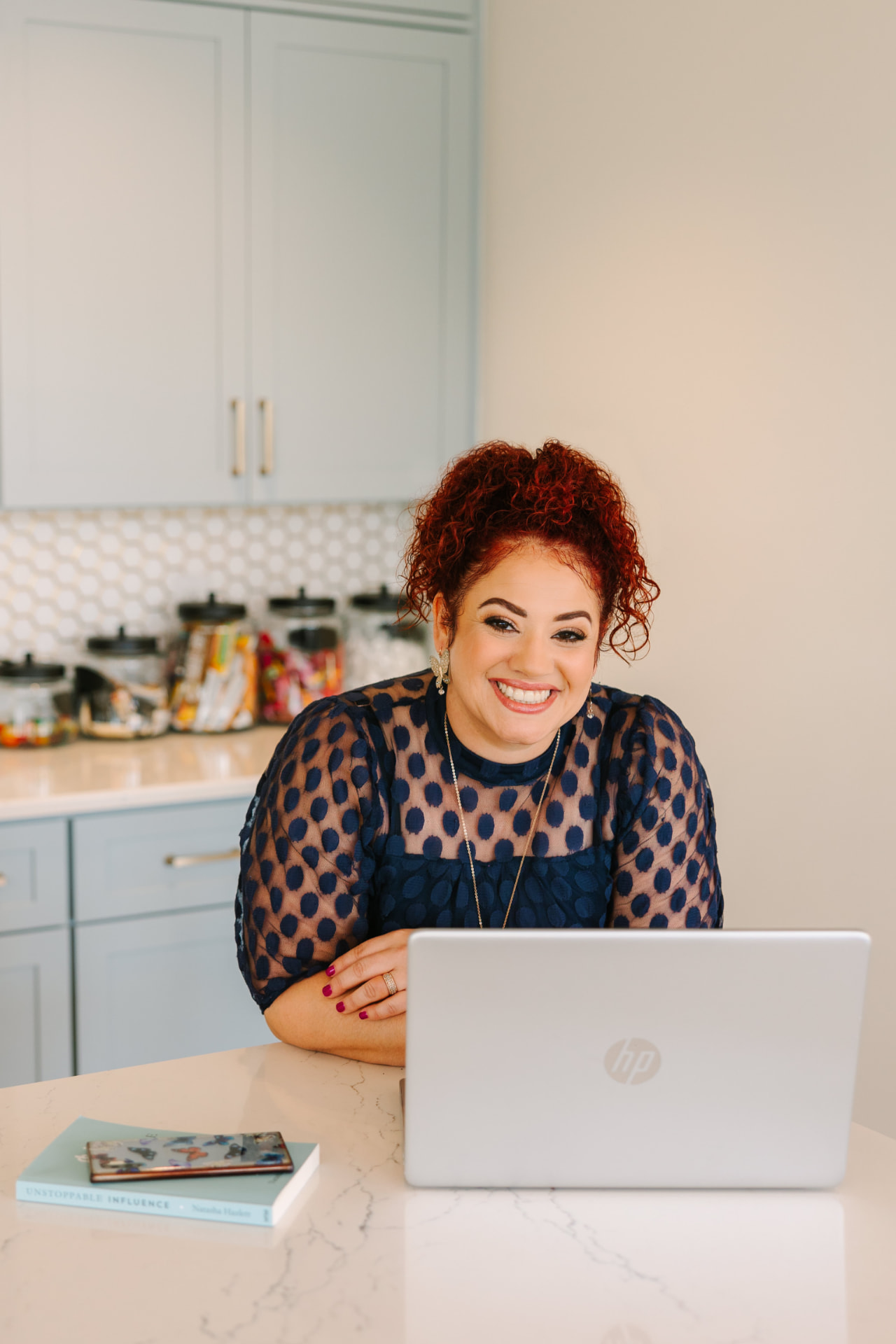 Branding portrait of a woman with red curly hair working at a laptop
