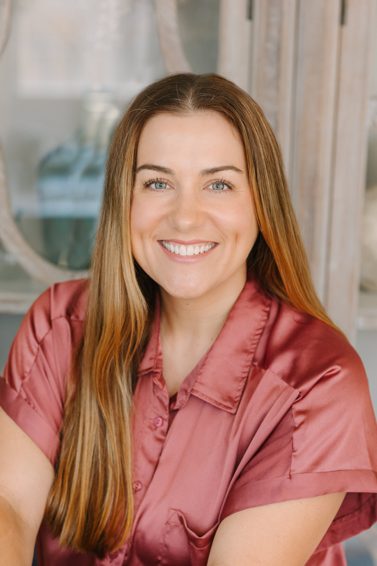 Professional headshot of a woman in a rose satin blouse